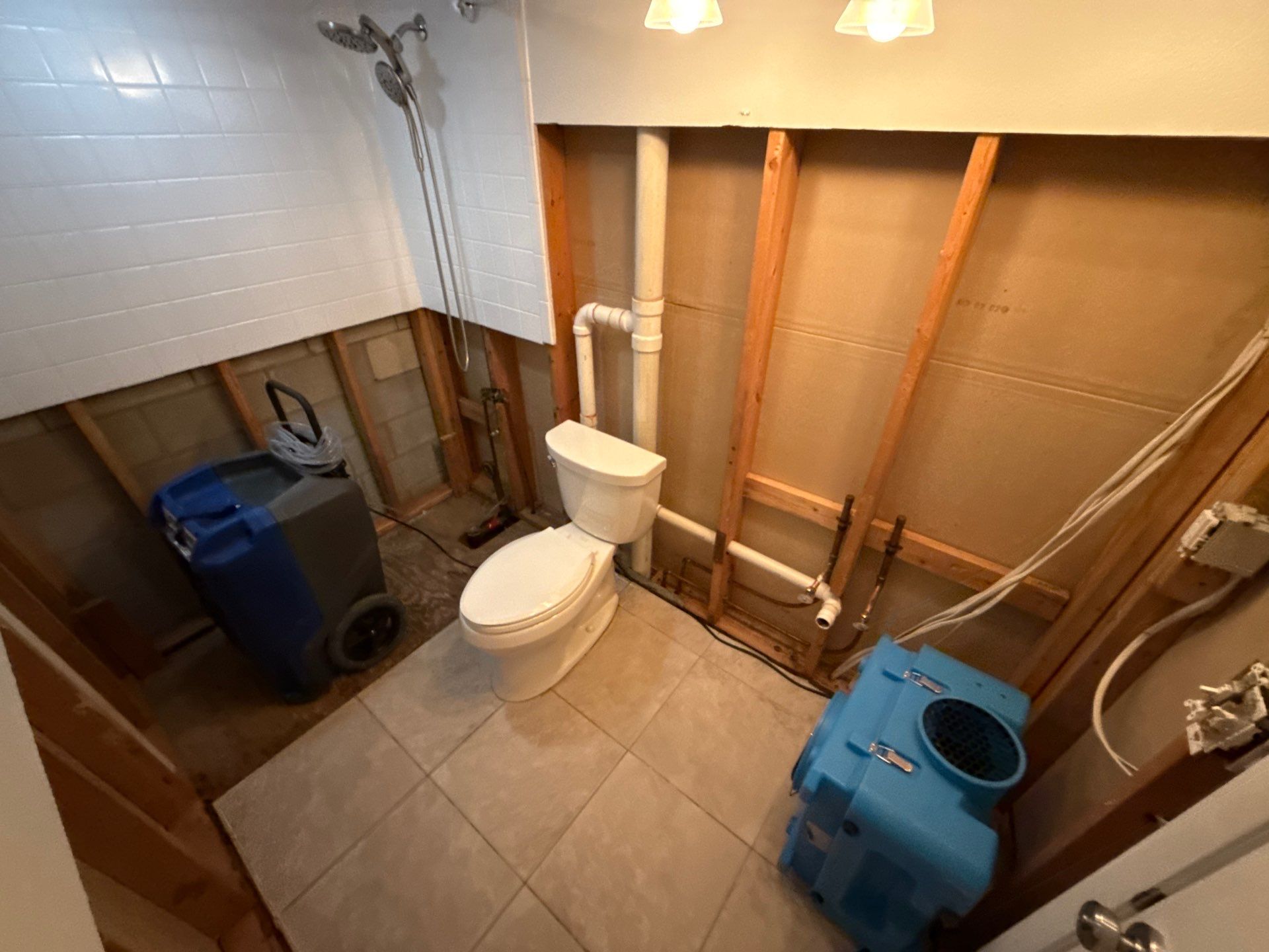 Professional dehumidifier and air scrubber setup in a gutted bathroom for structural drying and mold prevention.