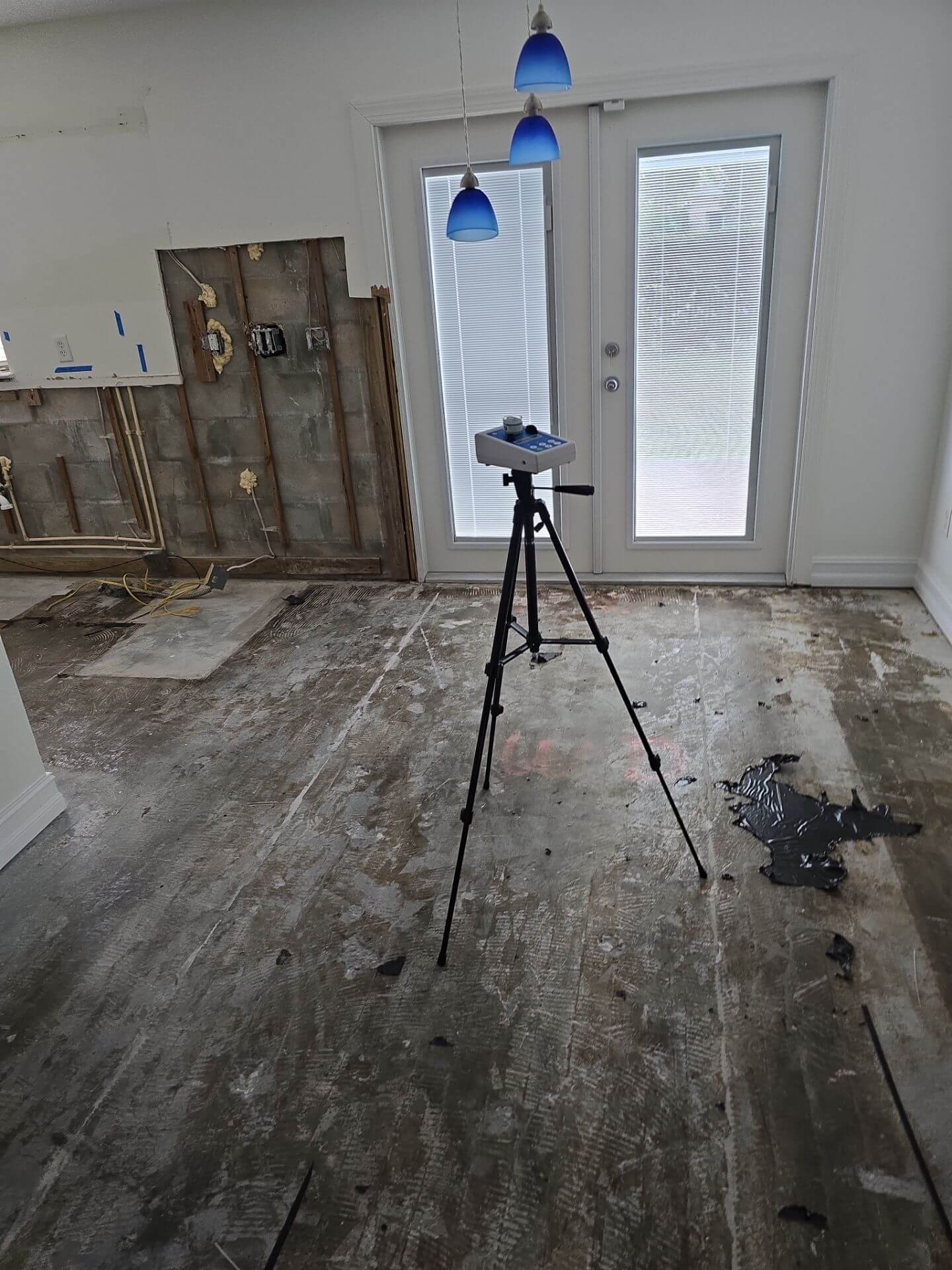 High-volume air sampling pump on a tripod performing mold spore testing in a stripped-down renovation area.