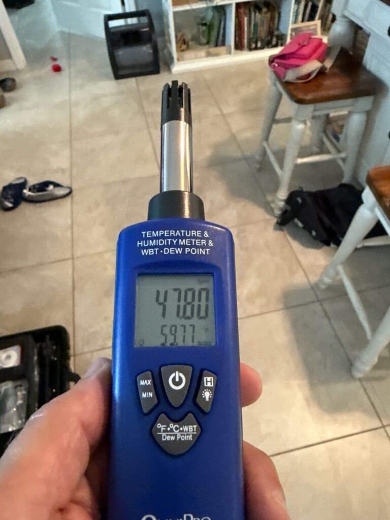 Professional hygrometer measuring indoor relative humidity and dew point during an environmental home inspection.