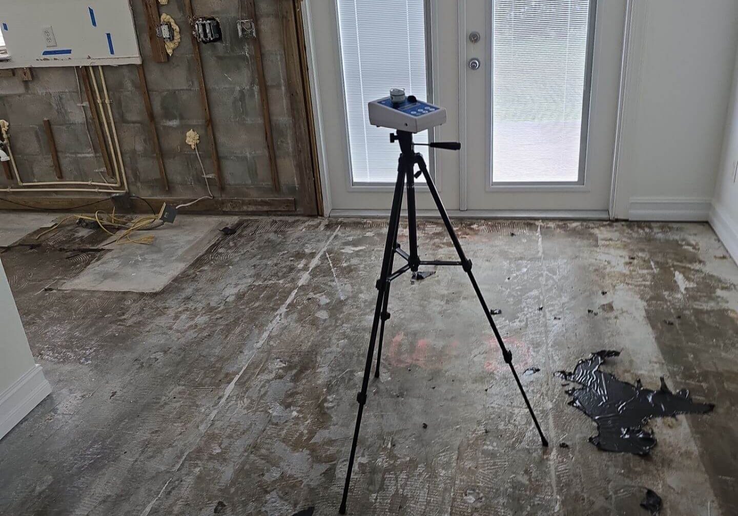 High-volume air sampling pump on a tripod performing mold spore testing in a stripped-down renovation area.