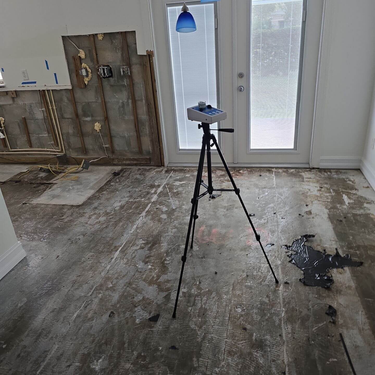High-volume air sampling pump on a tripod performing mold spore testing in a stripped-down renovation area.