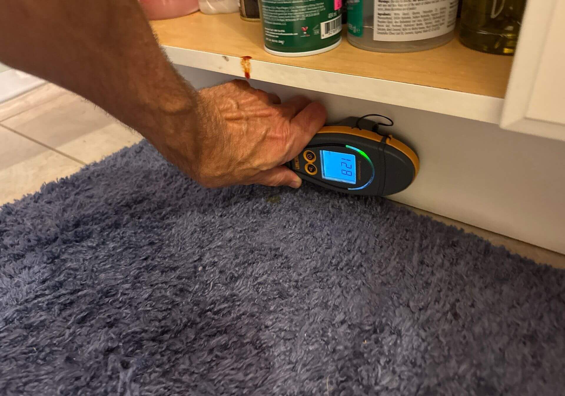 Technician using a moisture meter to check for leaks under a bathroom vanity cabinet for Marissa Umberger project.